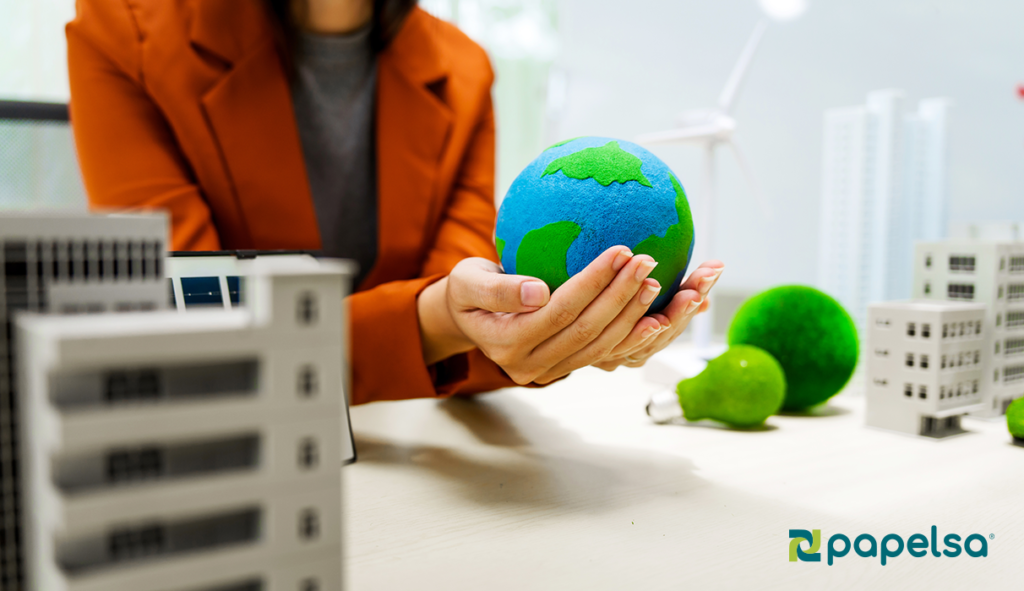 persona sosteniendo el mundo en sus manos sobre una maqueta de una ciudad simbolizando la sostenibilidad corporativa. 