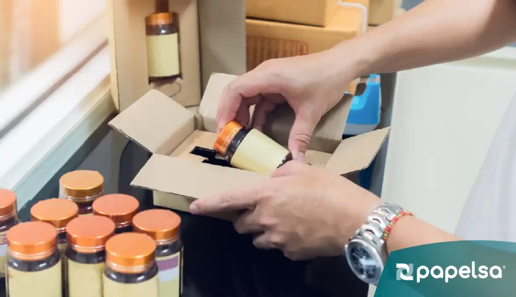 Persona acomodando un producto de una caja de cartón empaque secundario, junto a varios productos similares 