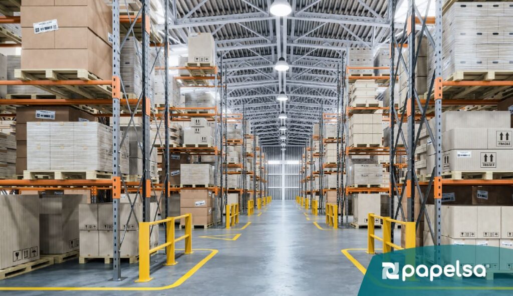 Almacén logístico con estanterías industriales y cajas de cartón corrugado organizadas sobre pallets, representando empaque terciario y almacenamiento eficiente