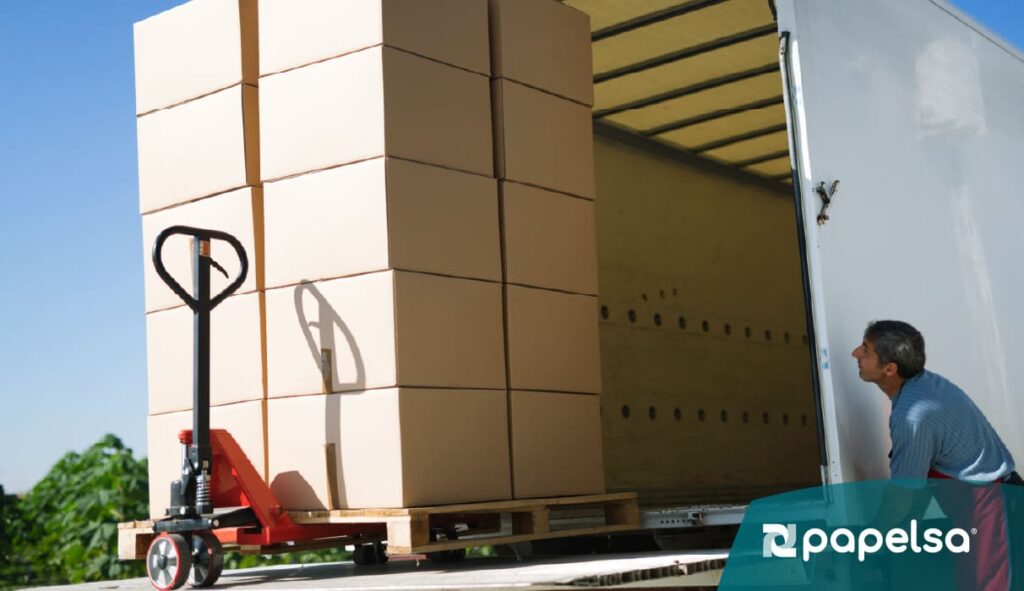 Carga de cajas de cartón corrugado sobre pallet siendo ingresada a camión, representando empaque terciario y eficiencia en transporte logístico