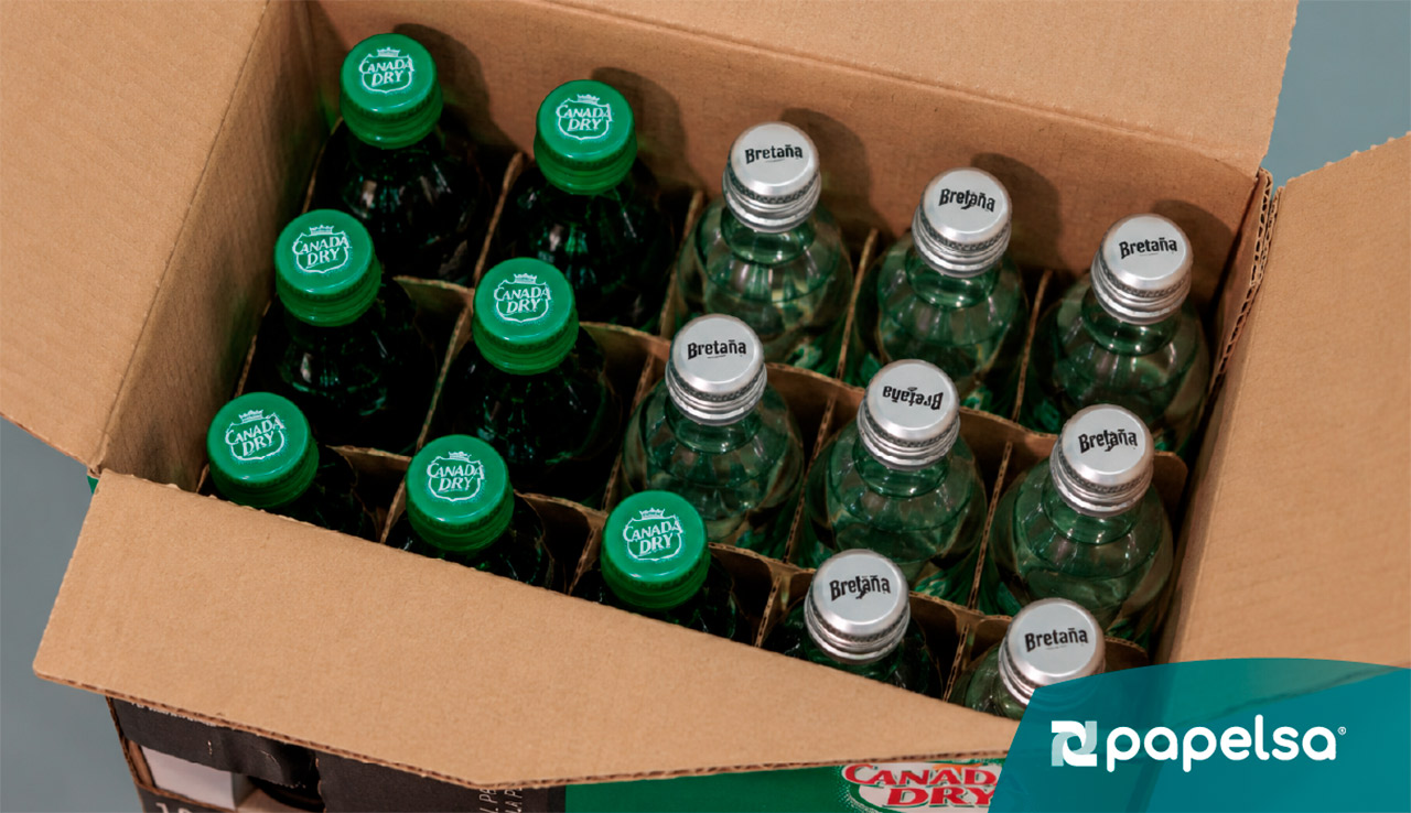 Caja de cartón abierta con botellas de bebidas Bretaña y Canada Dry organizadas en separadores.