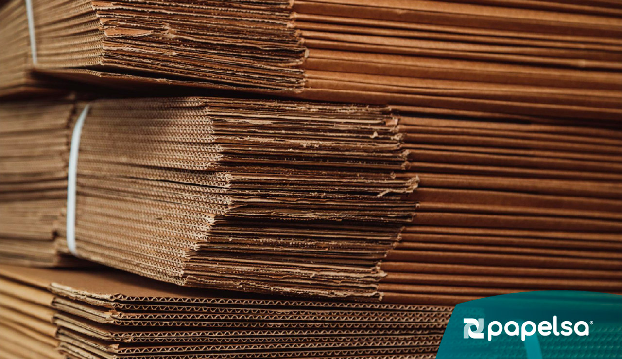 Pilas de láminas de cartón corrugado apiladas y sujetas con bandas de empaque.