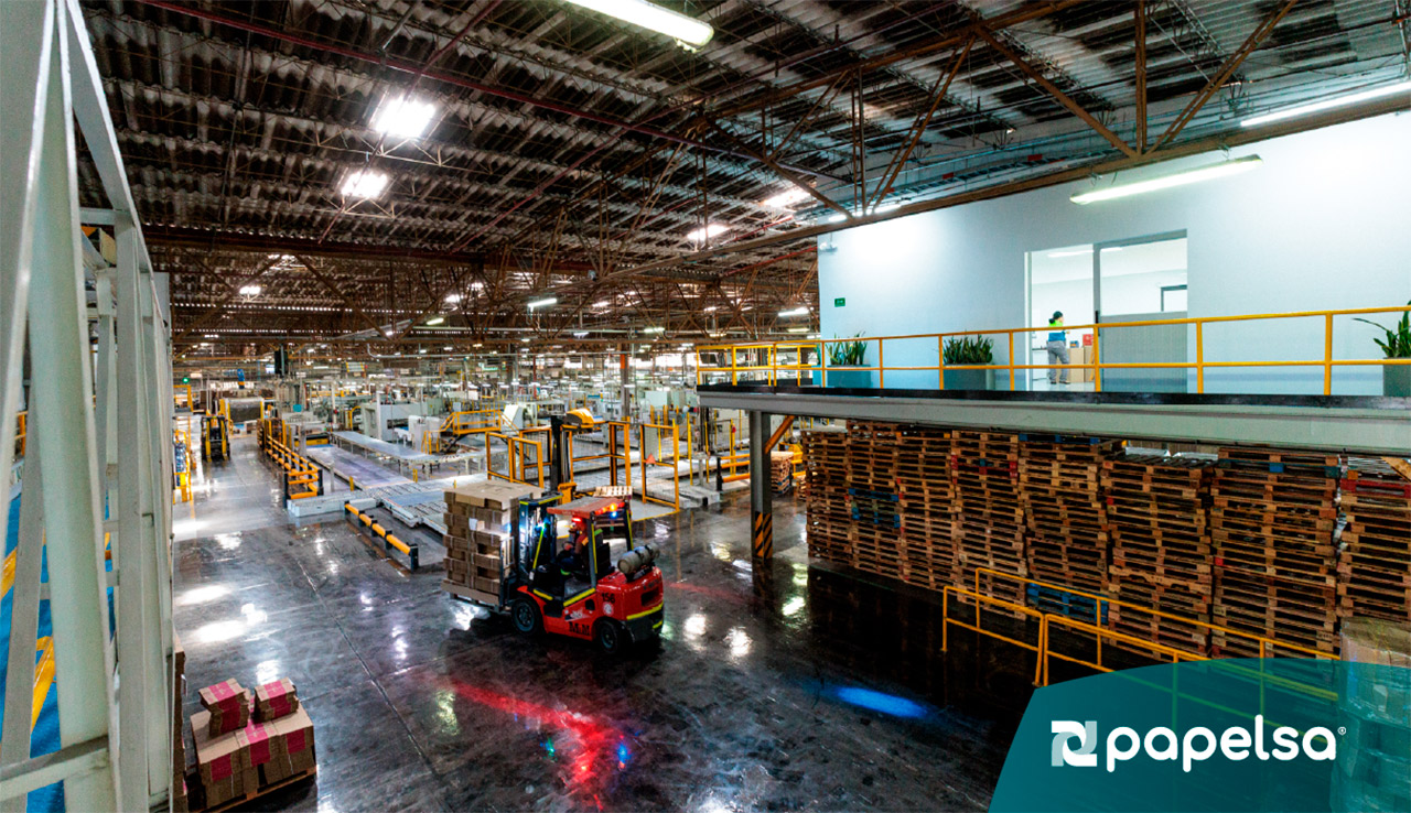 Camión de carga en un centro logístico con la compuerta trasera abierta, mostrando cajas de cartón corrugado hit y cajas de envío apiladas en su interior, listo para distribución desde el muelle de carga.
