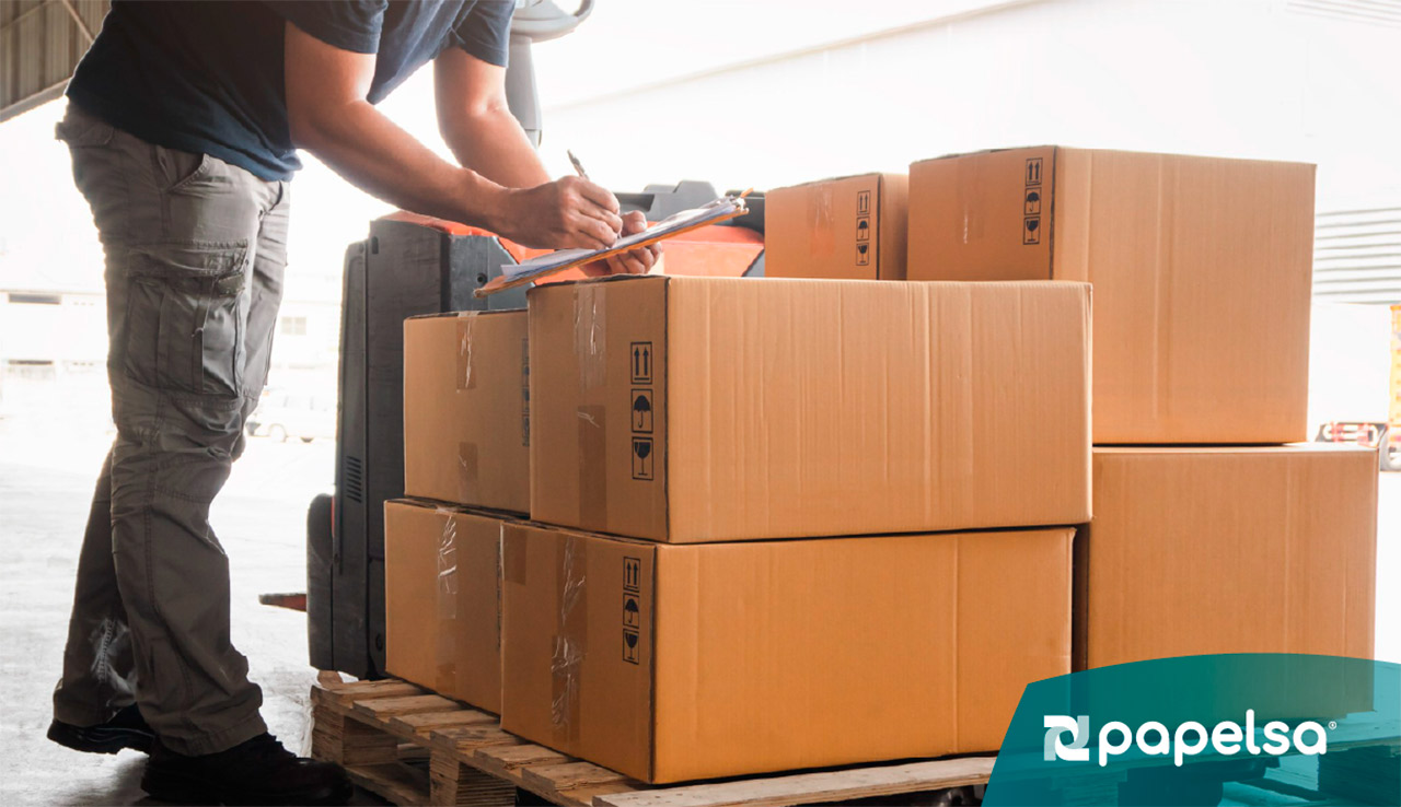 Cajas de cartón corrugado impresas para productos Hatsu Tea apiladas sobre un pallet de madera en un área de almacenamiento industrial.